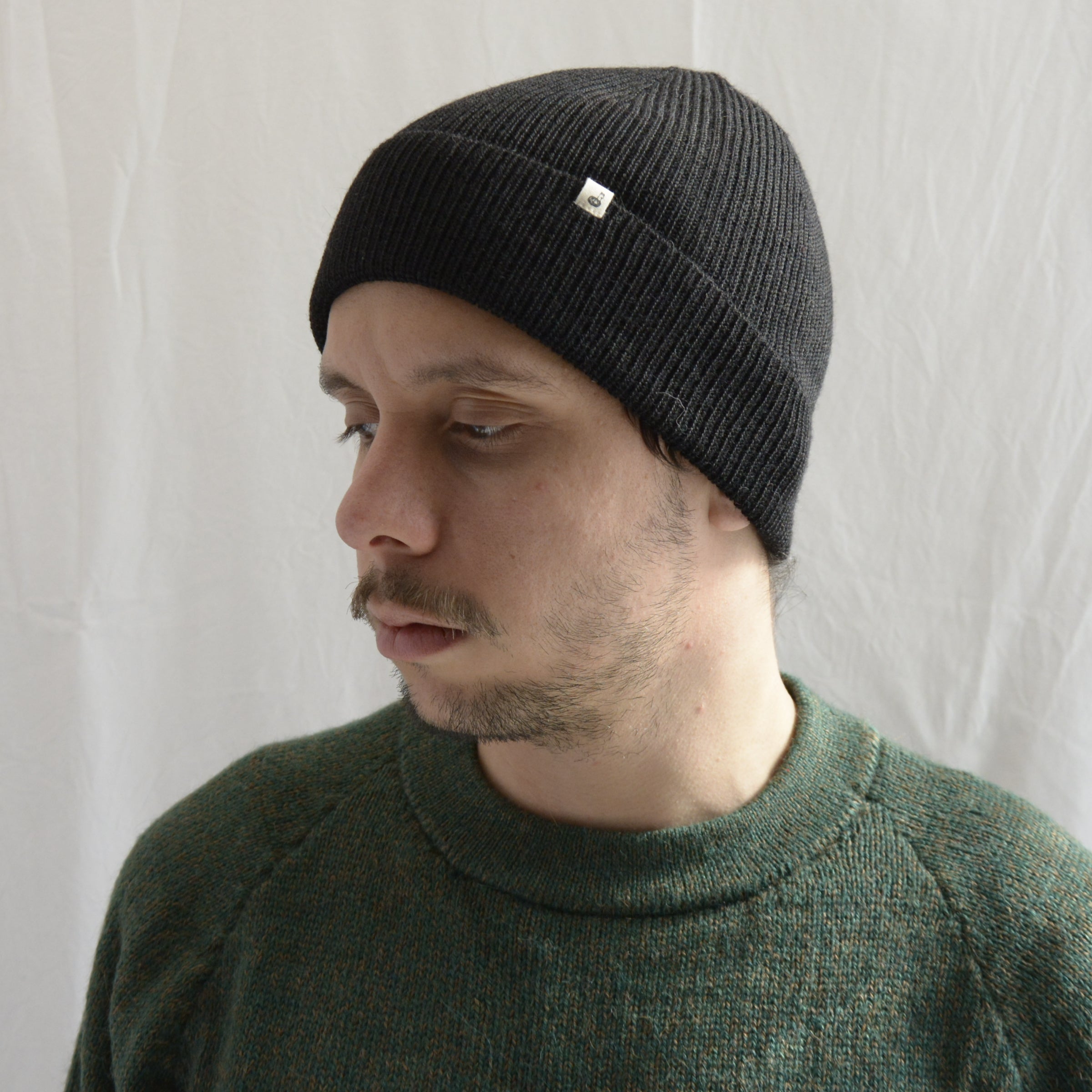 Man_wearing_alpaca_en_Peru_black_beanie_and_green_round_neck_sweater_and_looking_down_beside