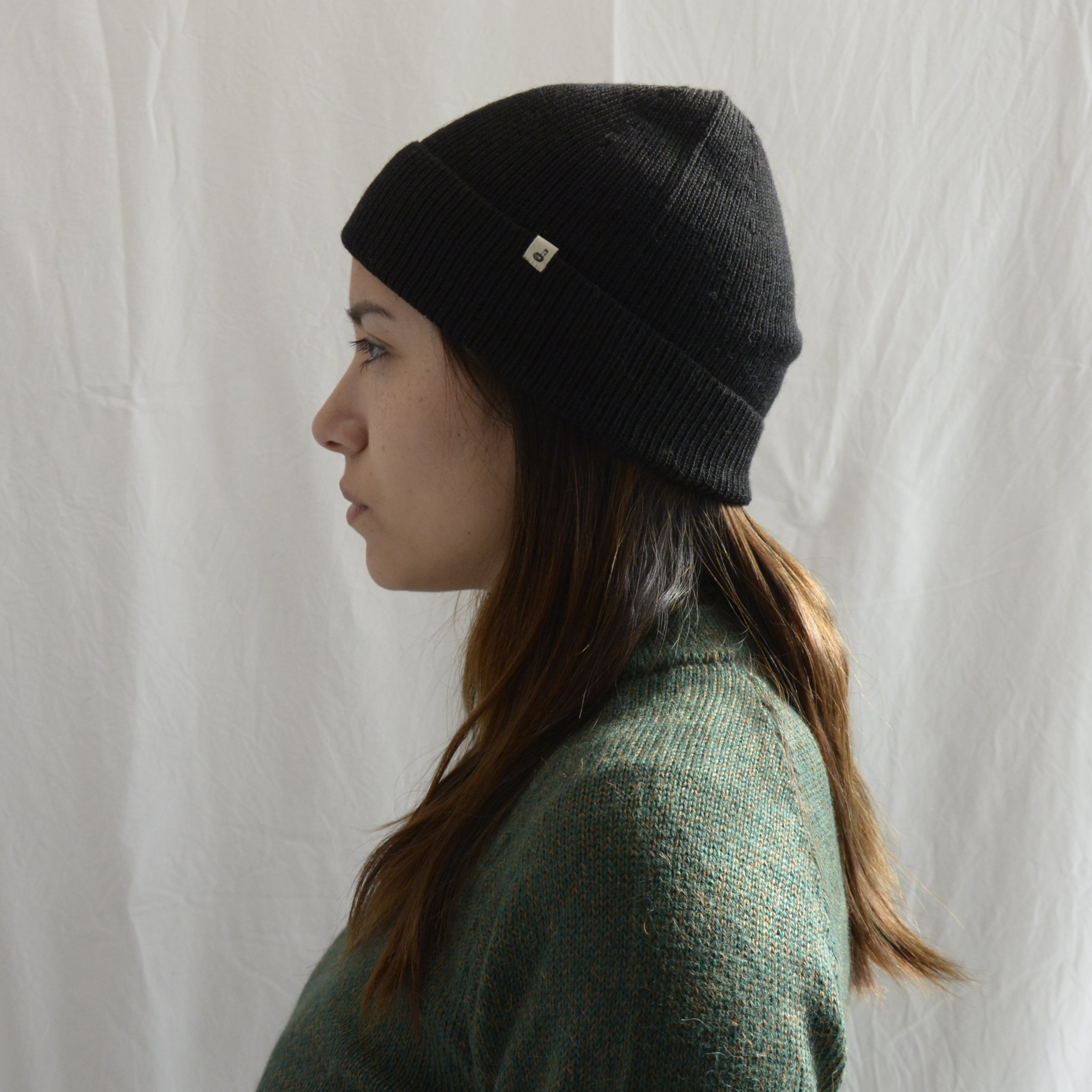 Woman_wearing_alpaca_en_Peru_black_beanie_and_green_round_neck_sweater