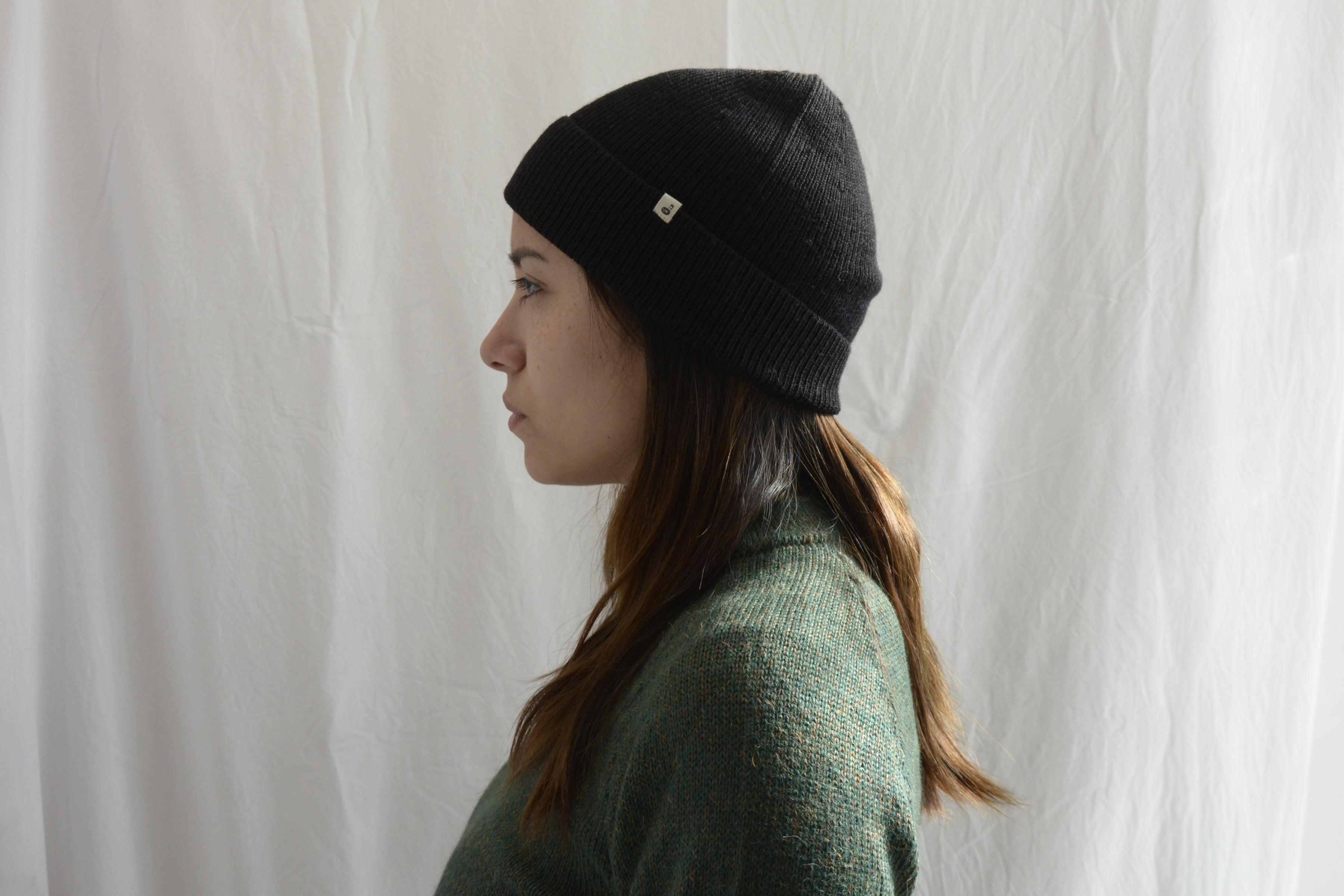 Woman_wearing_alpaca_en_Peru_black_beanie_and_green_round_neck_sweater