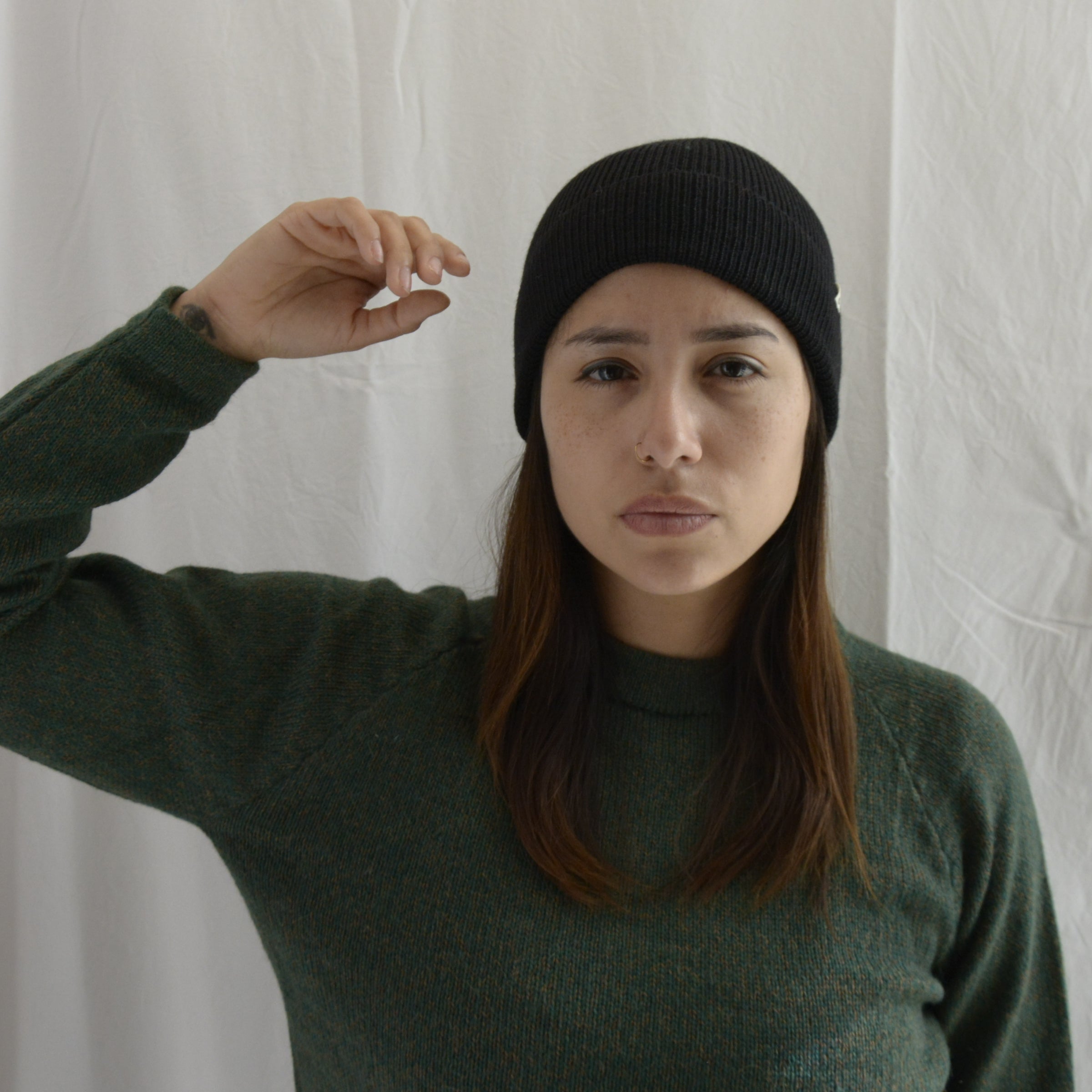 Woman_wearing_alpaca_en_Peru_black_beanie_and_green_round_neck_sweater_with_arm_up
