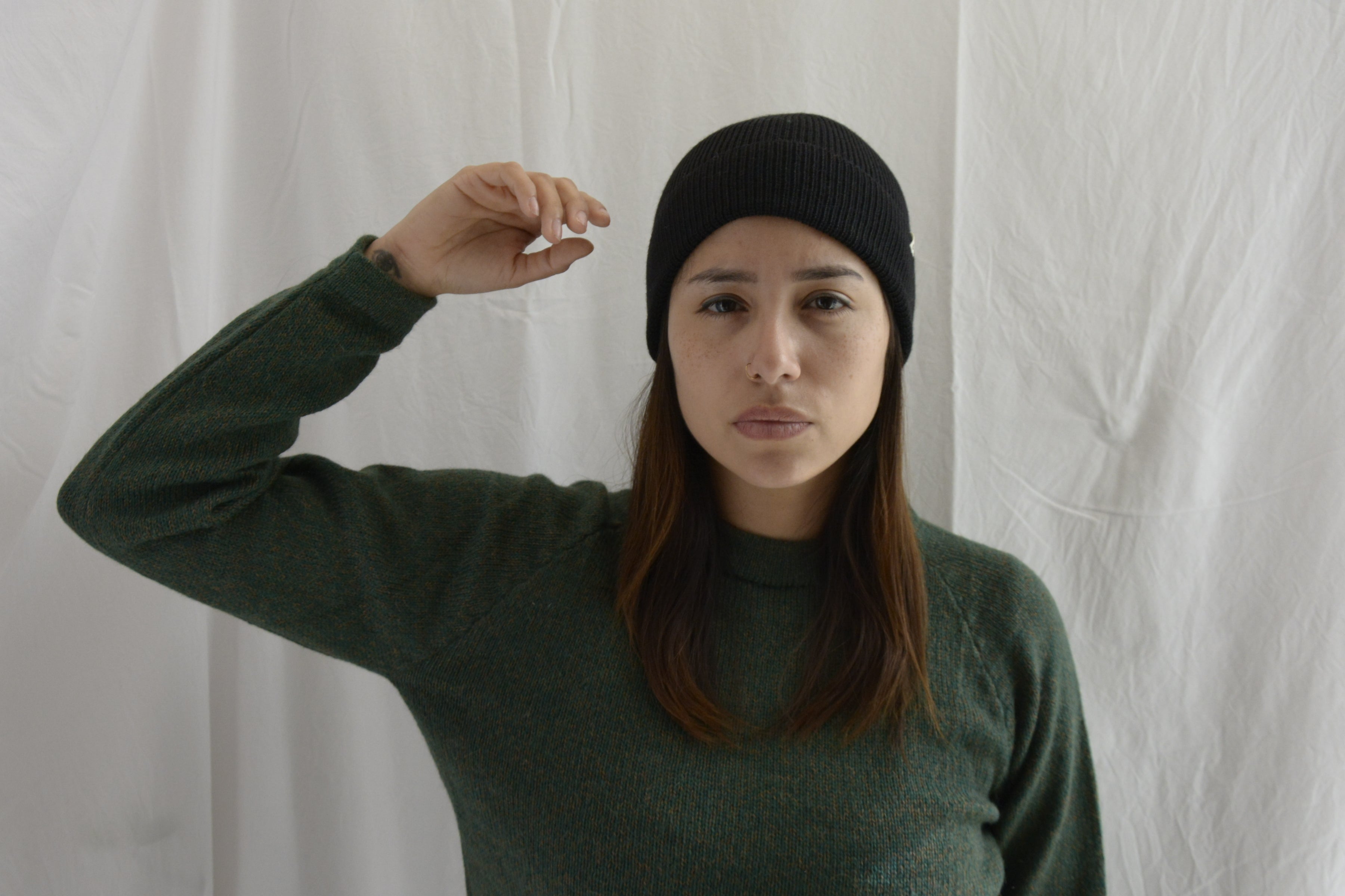 Woman_wearing_alpaca_en_Peru_black_beanie_and_green_round_neck_sweater_with_arm_up
