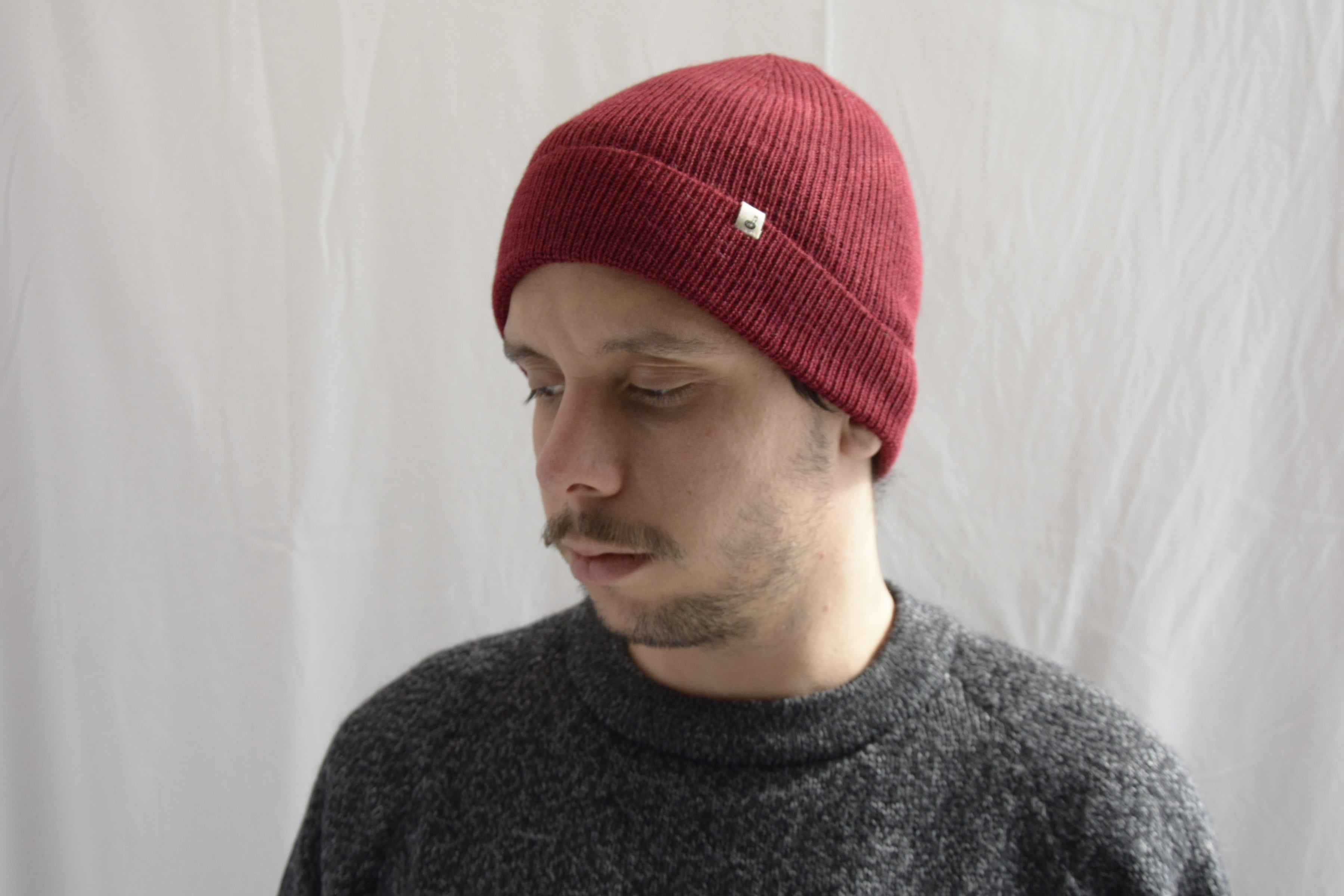 Man_wearing_alpaca_en_peru_brick_red_beanie_and_gray_round_neck_sweater_and_looking_down_beside