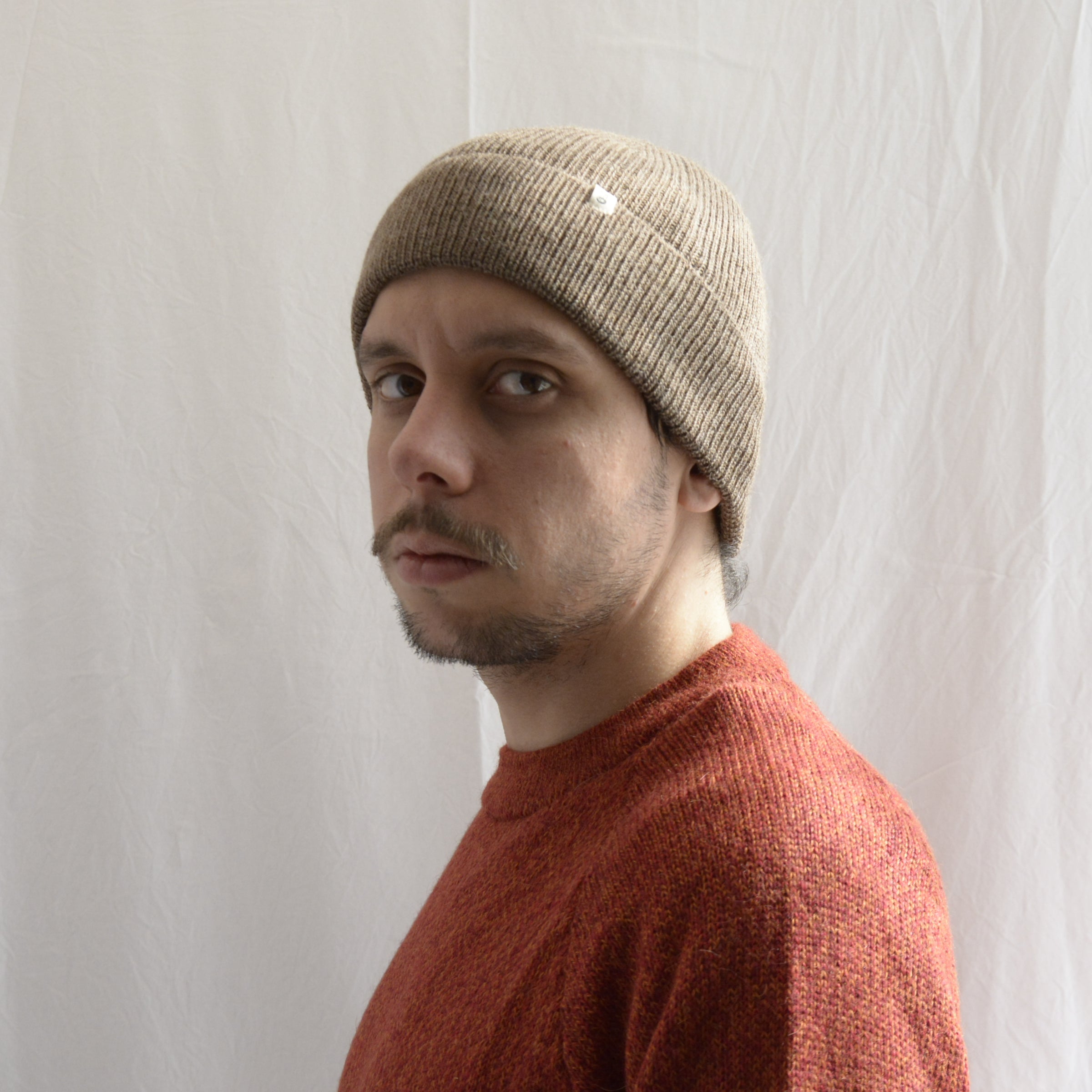 Man_wearing_alpaca_en_peru_coffee_beanie_and_orange_round_neck_sweater_and_looking_beside