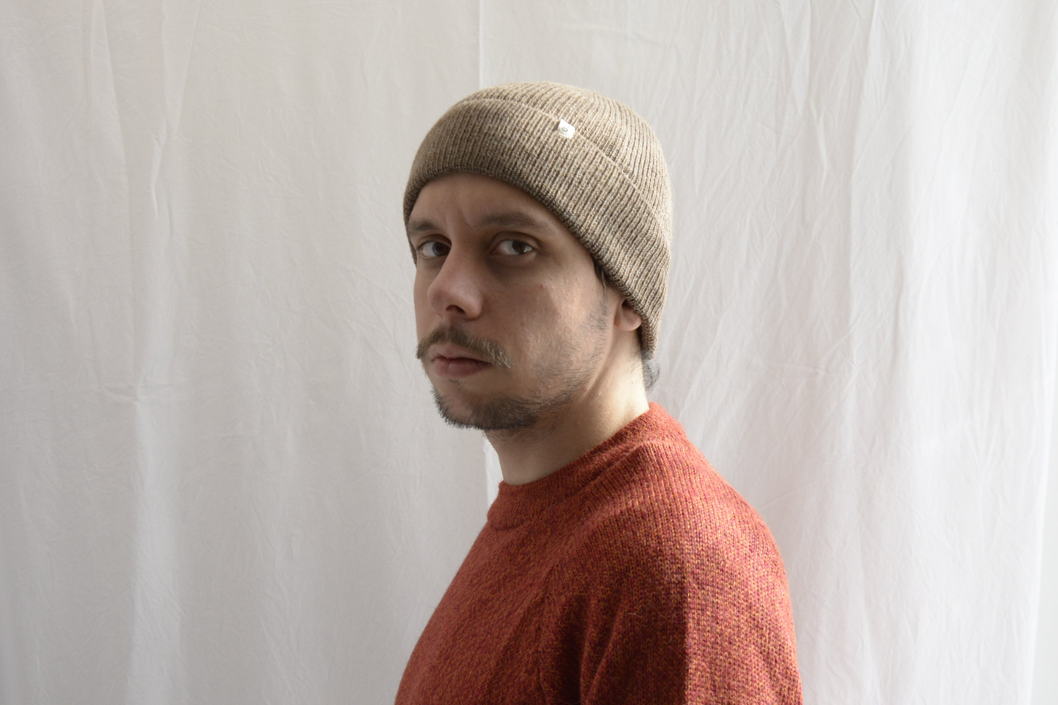 Man_wearing_alpaca_en_peru_coffee_beanie_and_orange_round_neck_sweater_and_looking_beside