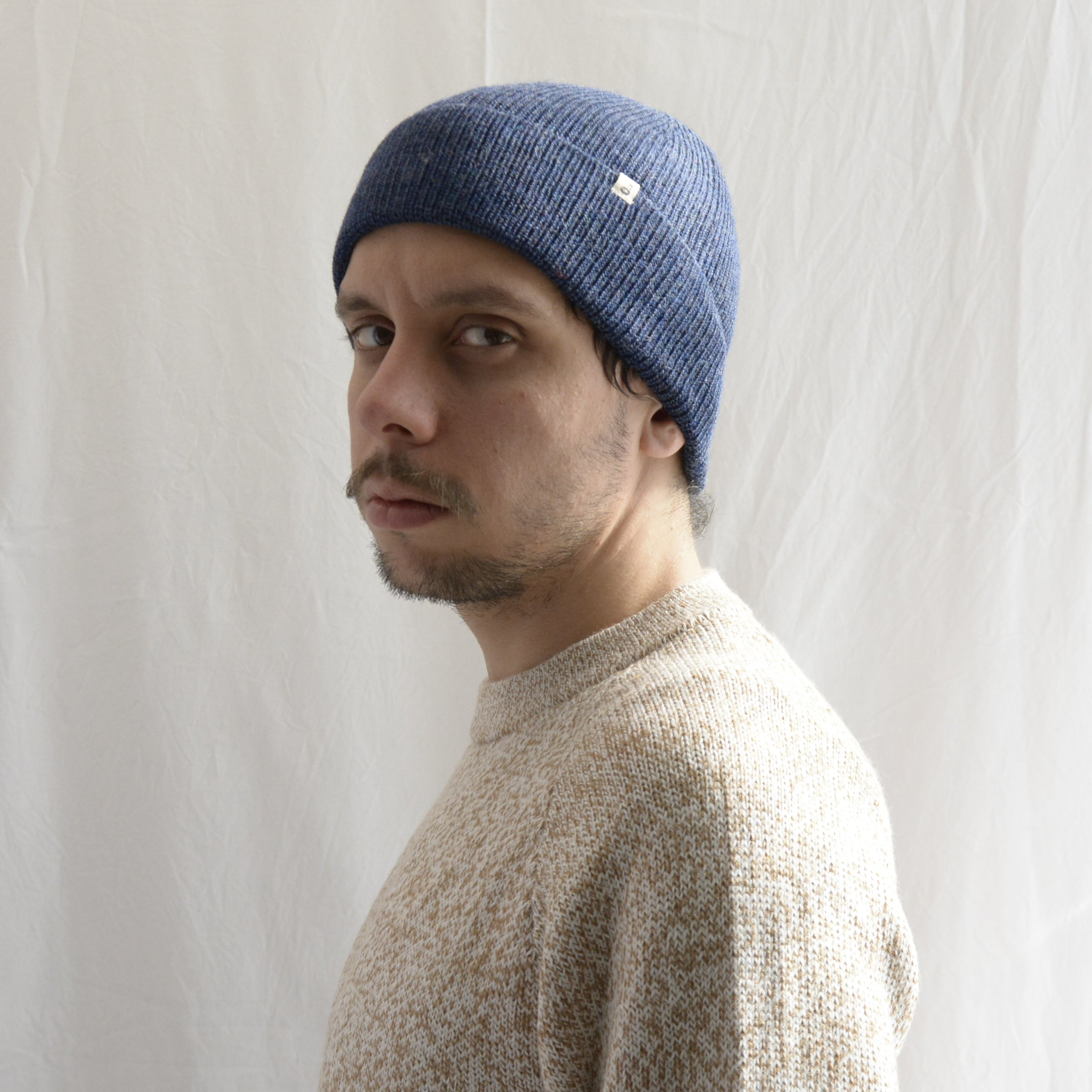 Man_wearing_alpaca_en_peru_steel_blue_beanie_and_beige_round_neck_sweater_and_looking_beside