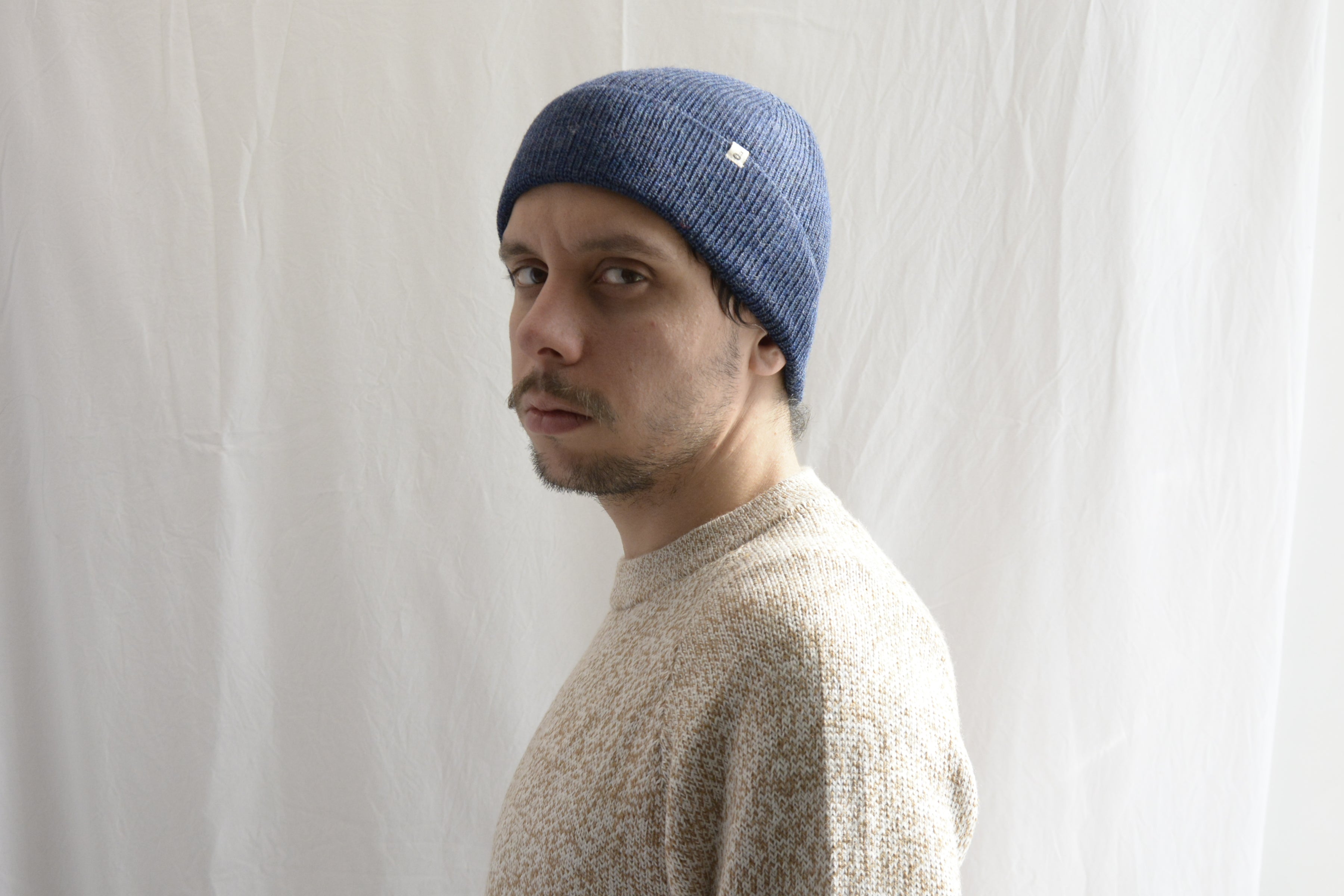 Man_wearing_alpaca_en_peru_steel_blue_beanie_and_beige_round_neck_sweater_and_looking_beside