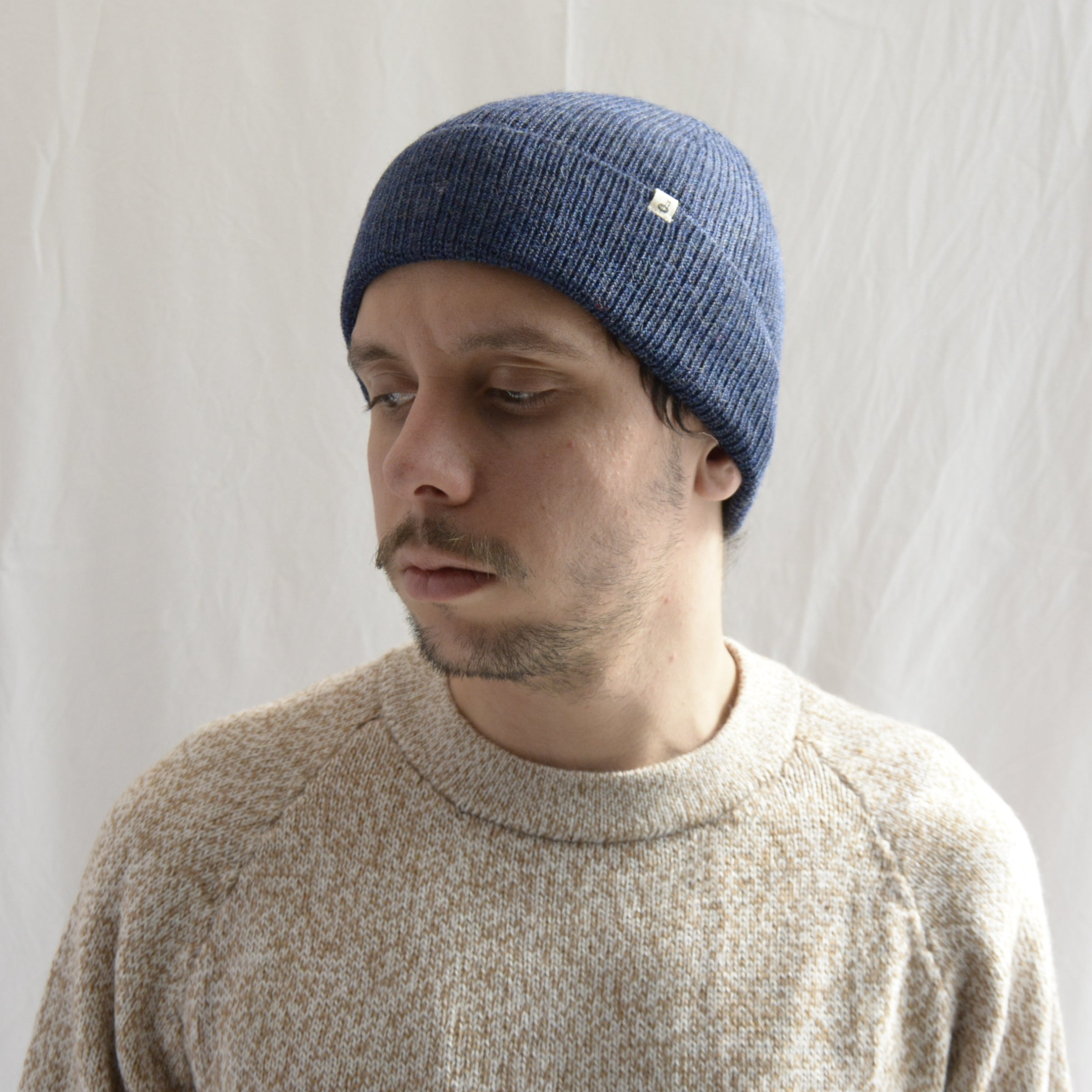Man_wearing_alpaca_en_Peru_steel_blue_beanie_and_beige_round_neck_sweater_and_looking_down_beside