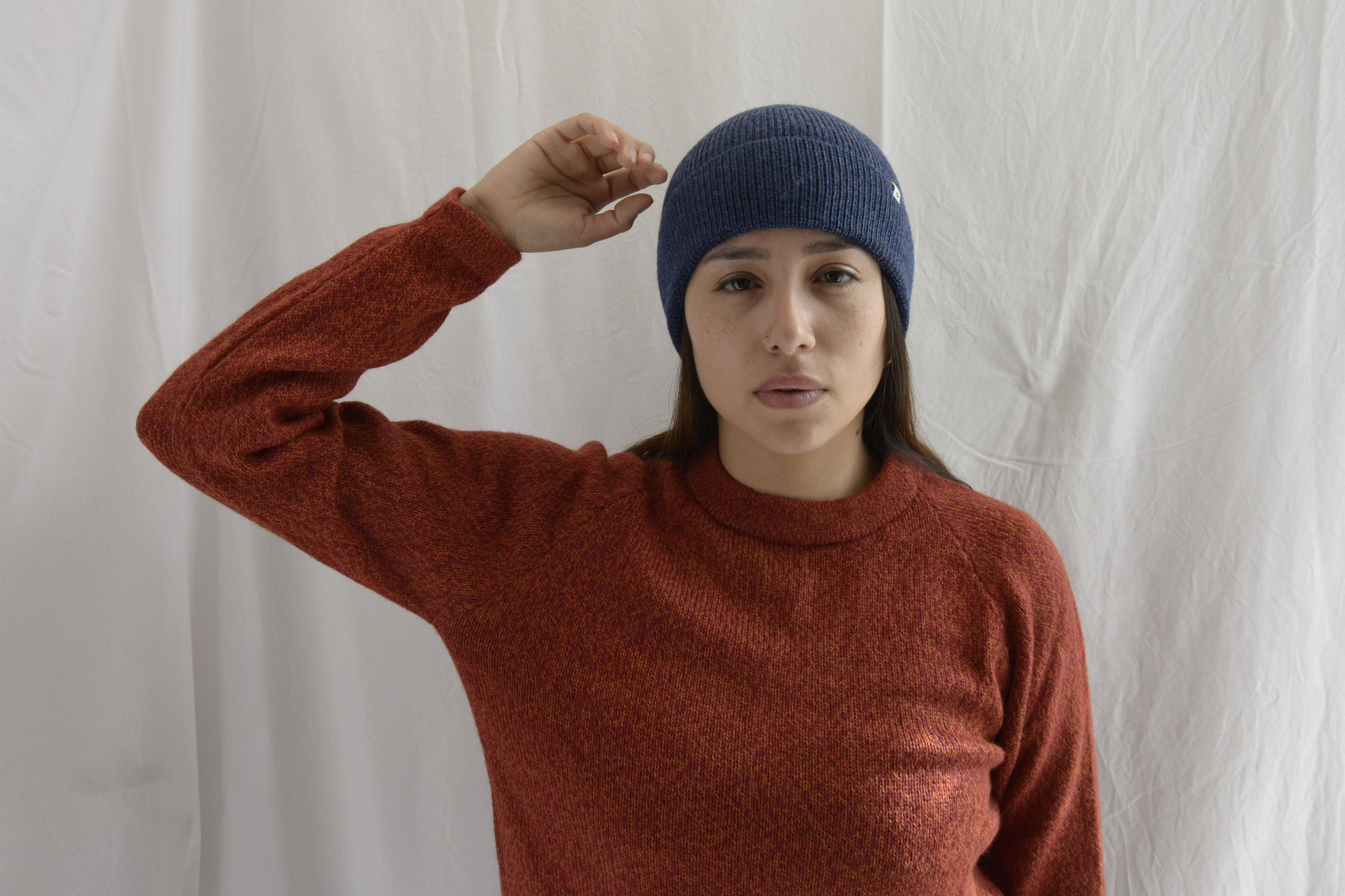 Woman_wearing_alpaca_en_peru_steel_blue_beanie_and_orange_round_neck_sweater_with_arm_up