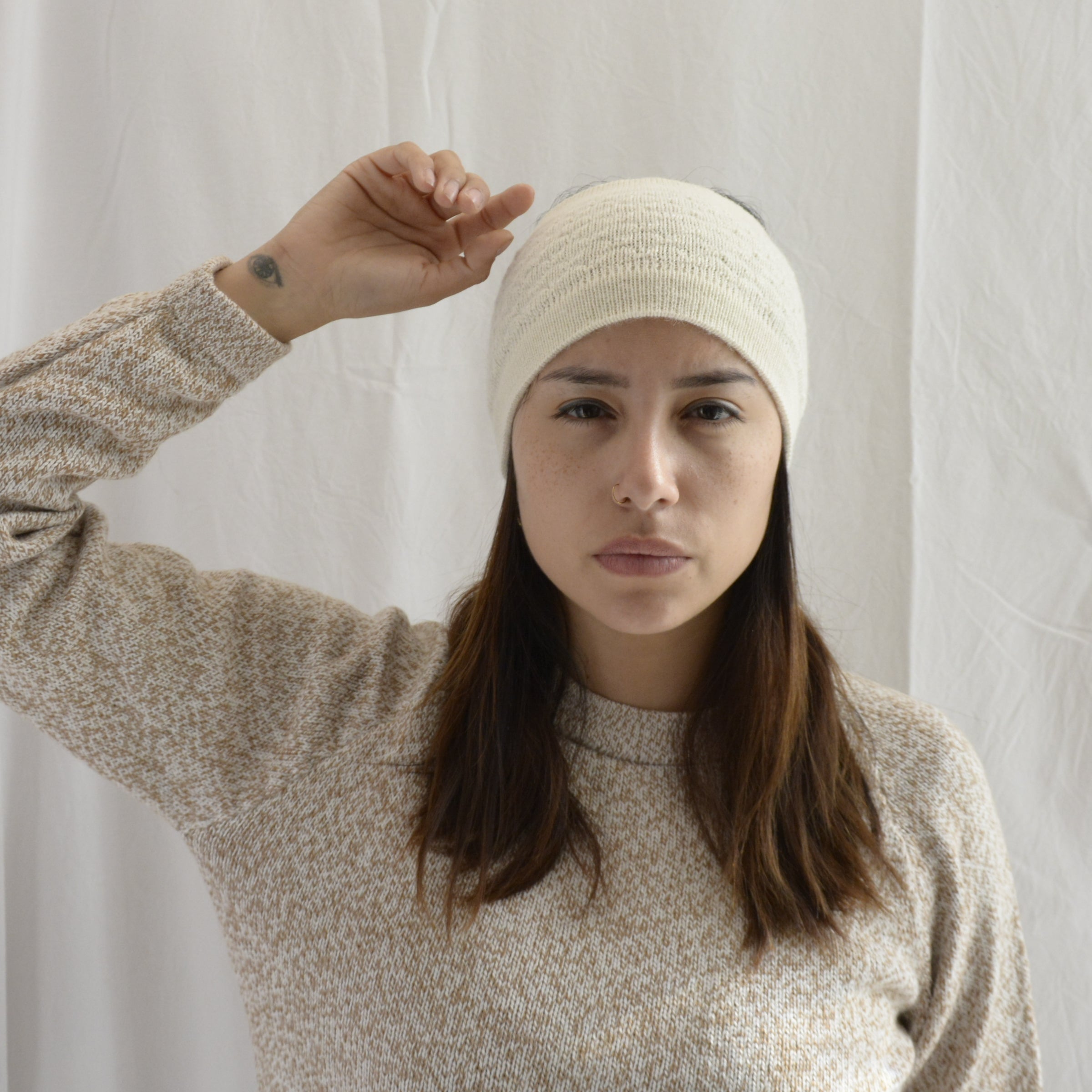 Woman_wearing_alpaca_en_Peru_white_head_band_and_cream_round_neck_sweater_with_arm_up