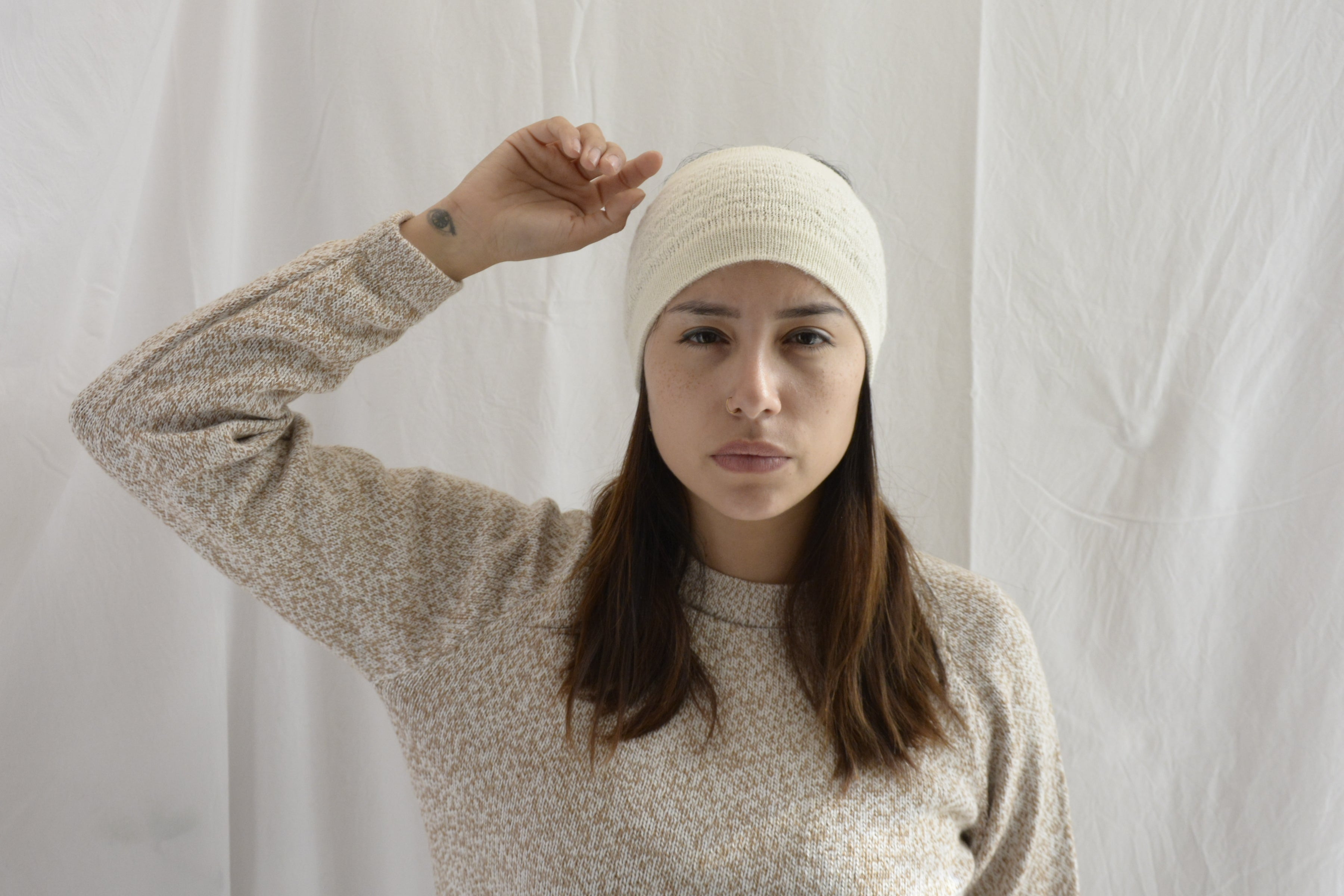 Woman_wearing_alpaca_en_Peru_white_head_band_and_cream_round_neck_sweater_with_arm_up