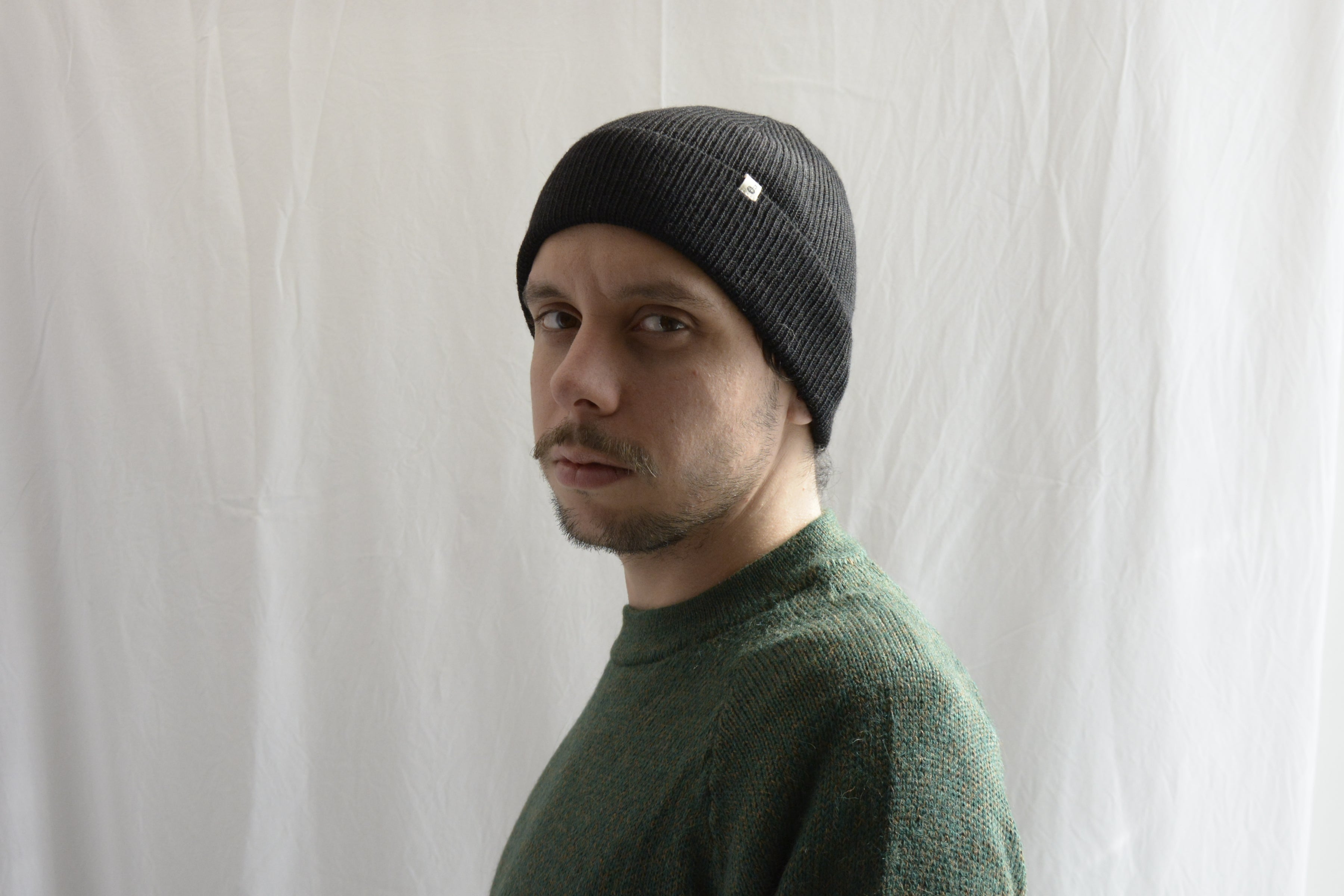 Man_wearing_alpaca_en_peru_black_beanie_and_green_round_neck_sweater_and_looking_beside