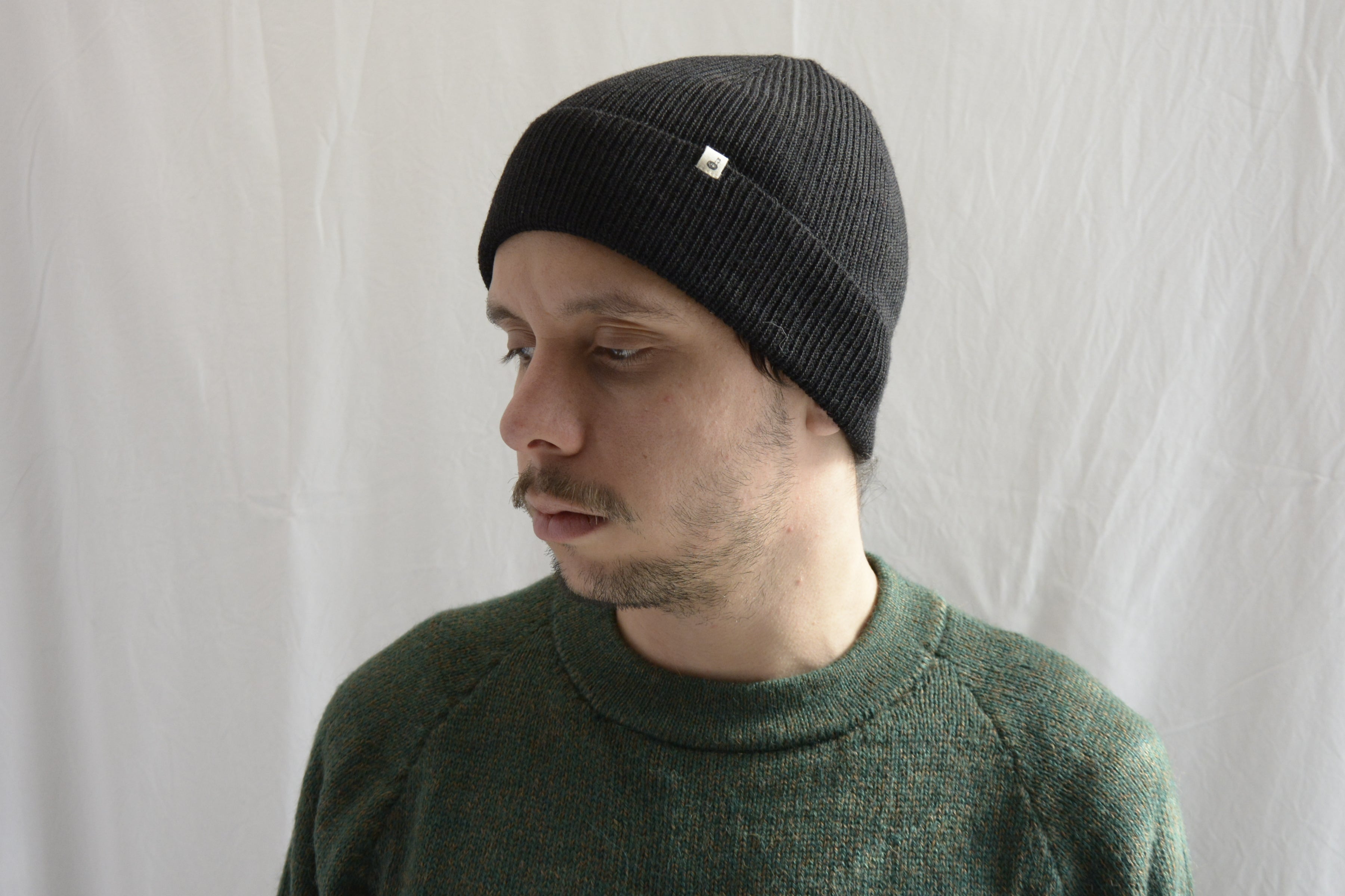 Man_wearing_alpaca_en_Peru_black_beanie_and_green_round_neck_sweater_and_looking_down_beside