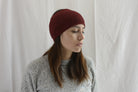 Woman_wearing_alpaca_en_peru_brick_red_head_band_and_light_grey_rond_neck_sweater_and_look_down_beside