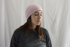 Woman_wearing_alpaca_en_peru_pink_beanie_and_gray_round_neck_sweater_and_looking_down_beside


