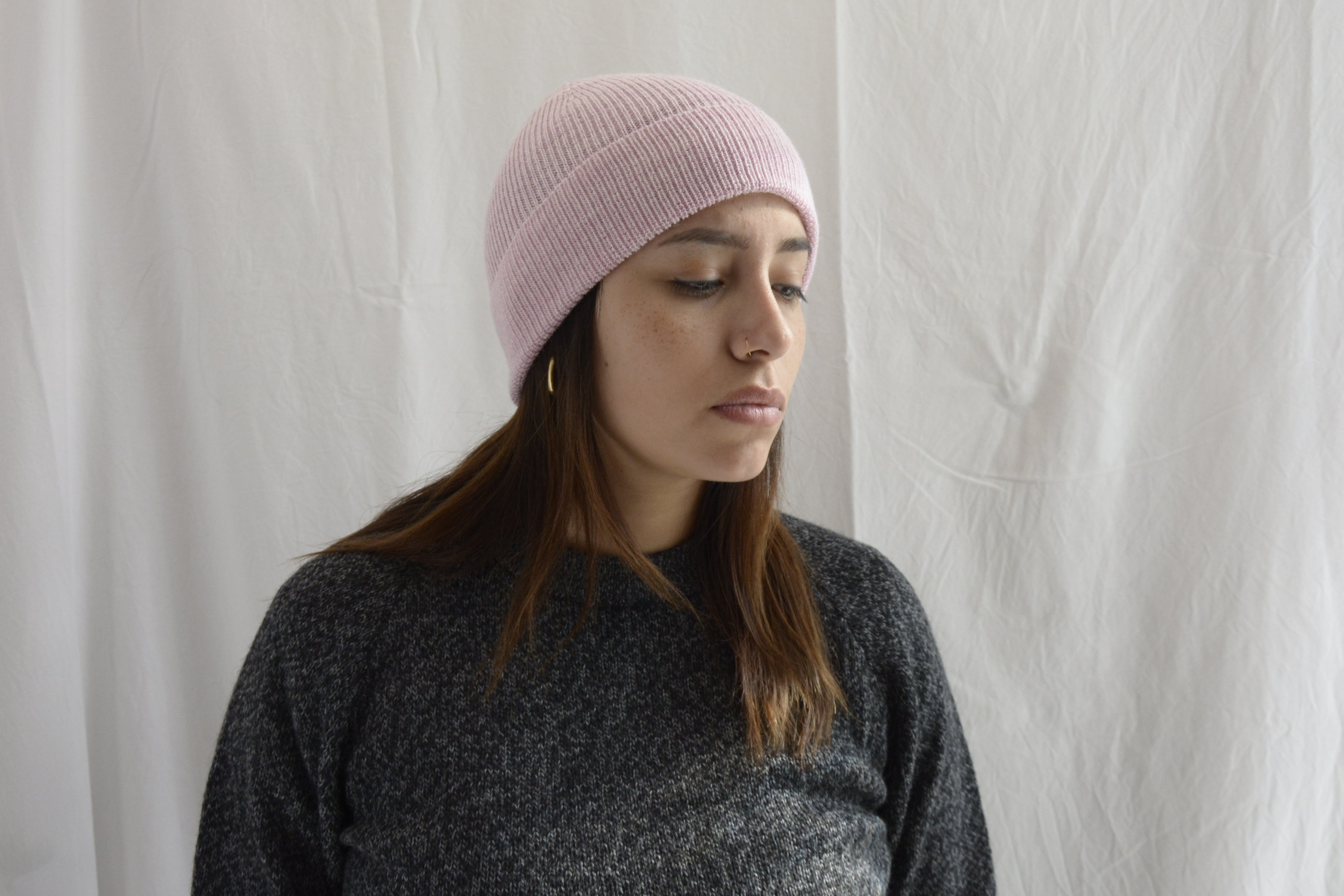 Woman_wearing_alpaca_en_peru_pink_beanie_and_gray_round_neck_sweater_and_looking_down_beside

