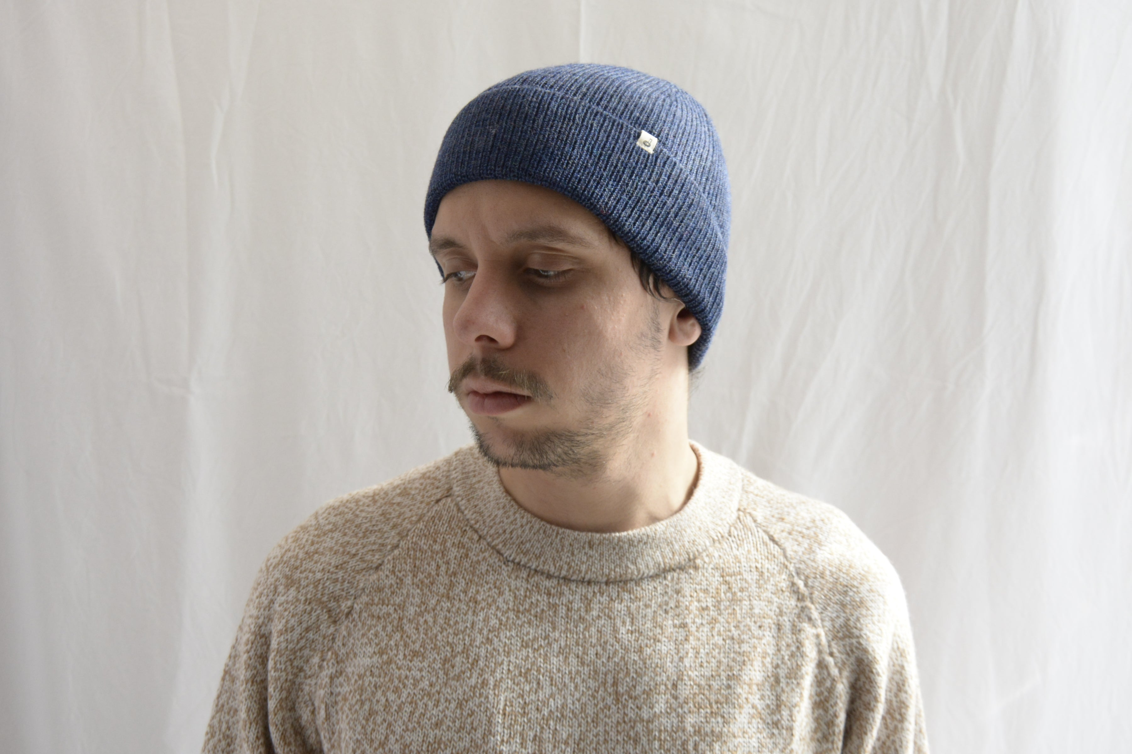 Man_wearing_alpaca_en_Peru_steel_blue_beanie_and_beige_round_neck_sweater_and_looking_down_beside