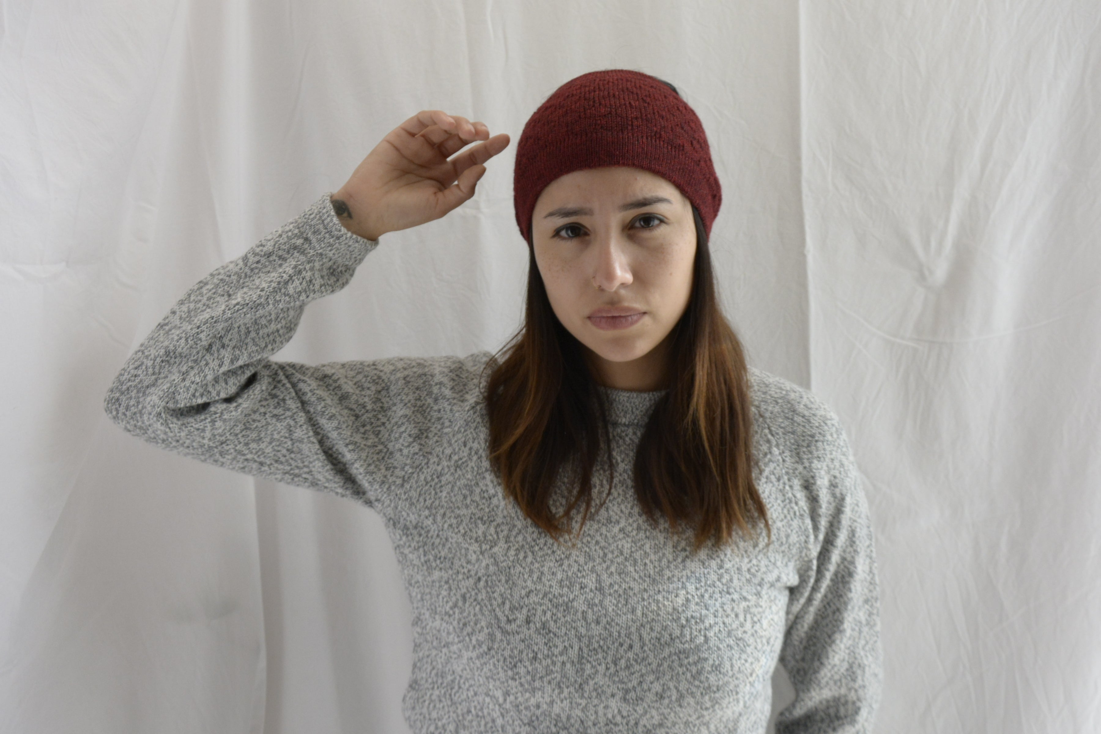 Woman_wearing_alpaca_en_peru_brick_red_head_band_and_light_grey_rond_neck_sweater_with_arm_up