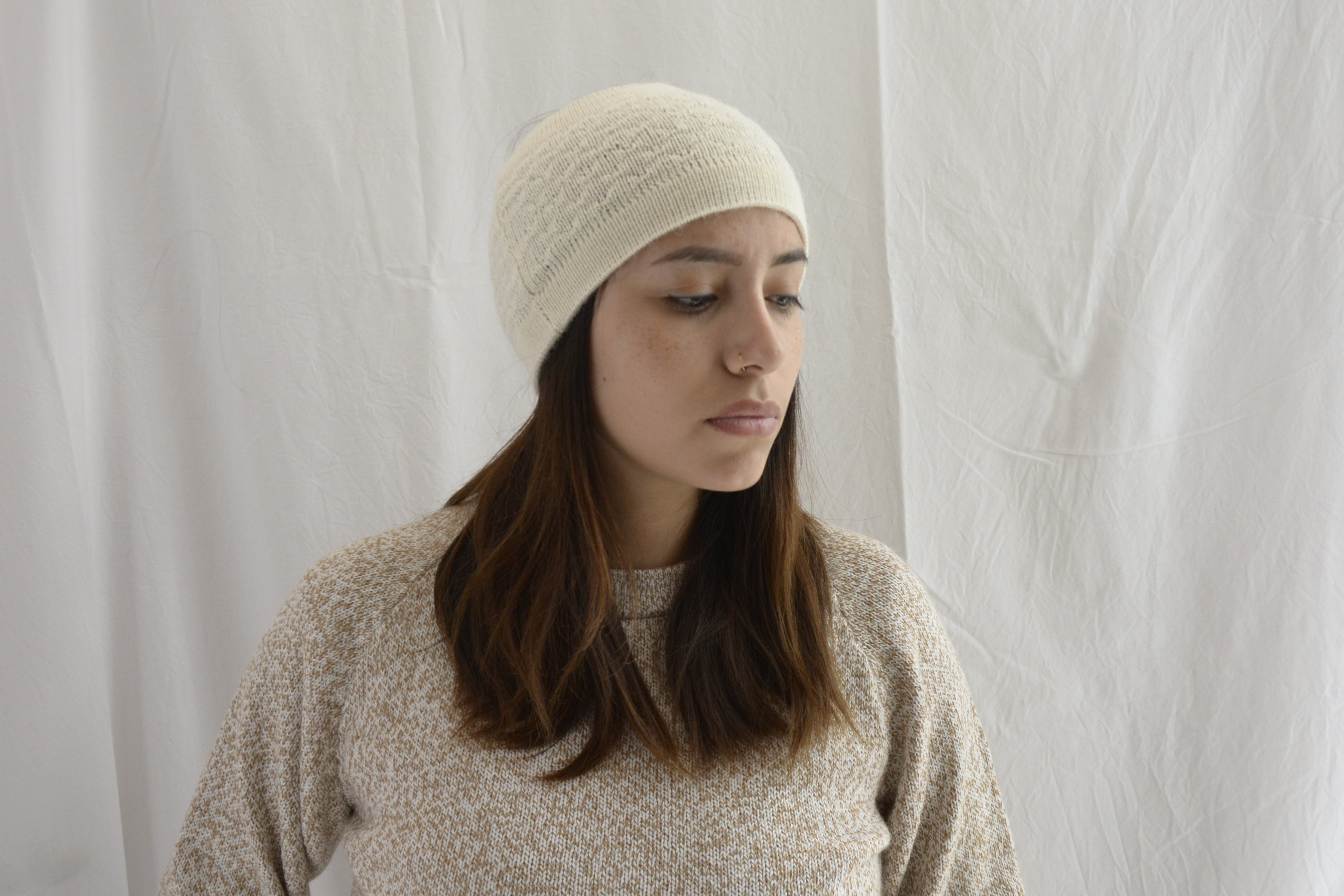 Woman_wearing_alpaca_en_Peru_white_head_band_and_cream_round_neck_sweater_and_looking_down_beside